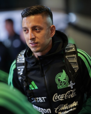 Un futbolista con una chaqueta deportiva negra y verde con el escudo de México y las tiras de una mochila