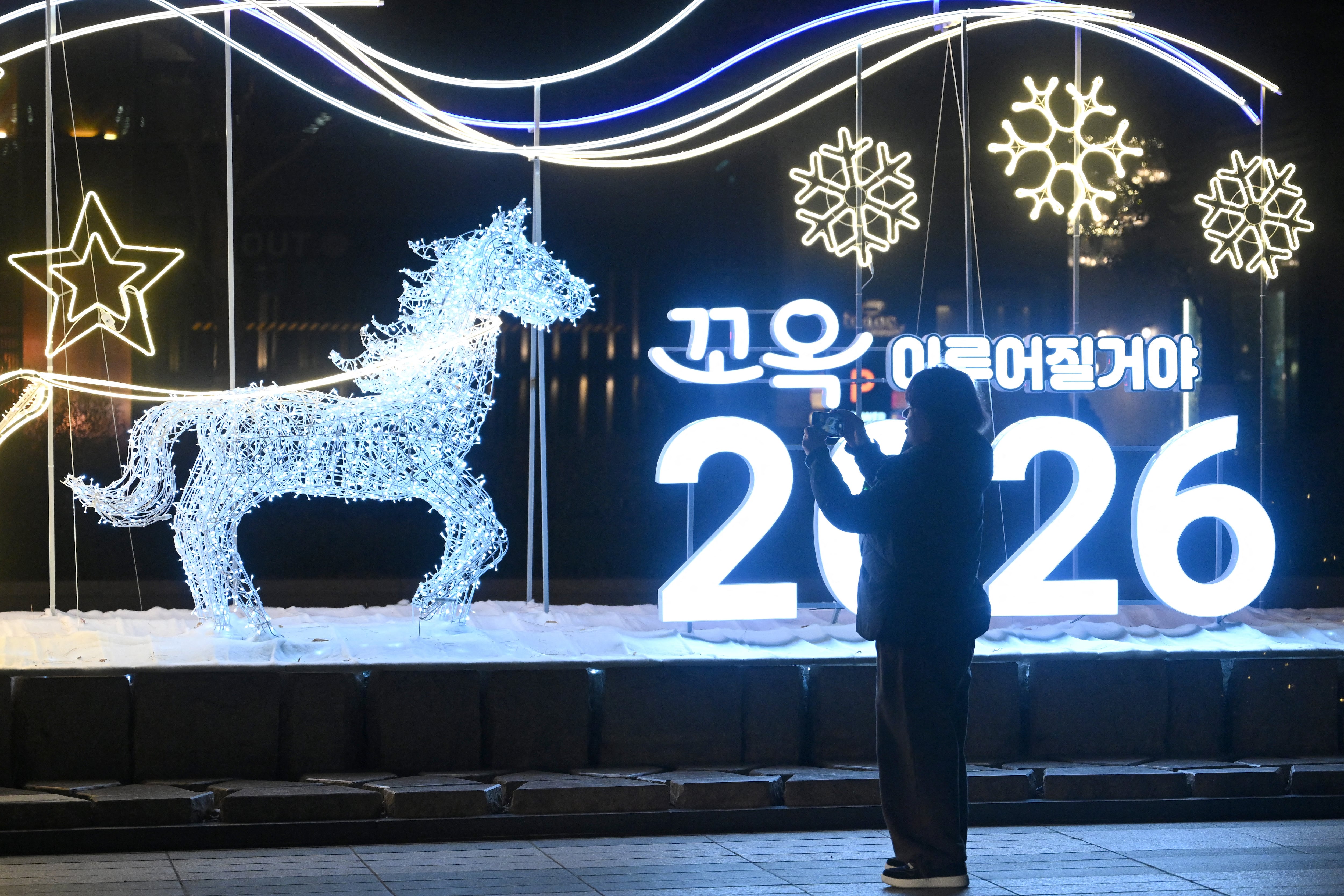 Una mujer se fotografía frente a un letrero luminoso de