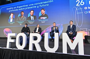 Cuatro hombres sentados en un escenario detrás de letras que forman la palabra FORUM frente a una pantalla con el título Crédito en Argentina