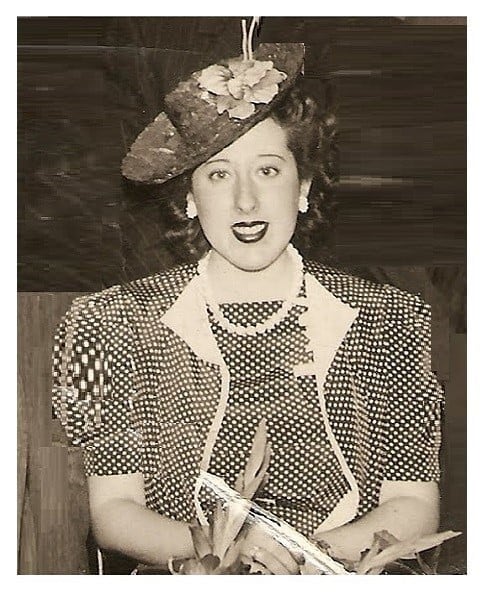 La icónica actriz Nelly Lainez posa con elegancia, luciendo un sombrero decorado, un collar de perlas y un atuendo de lunares, reflejando su carisma.