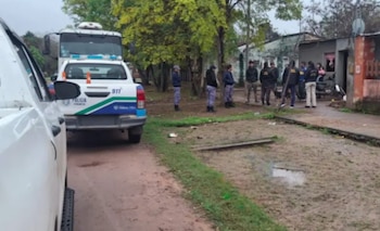 Carros de polícia e polícia do Chaco em estradas de terra. Você pode ver pessoas, prédios baixos e árvores em uma área residencial
