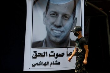 Un manifestante iraquí usa una máscara protectora cuando pasa junto a un póster que representa al ex asesor gubernamental y analista político Hisham al-Hashemi, quien fue asesinado por hombres armados, en la plaza Tahrir en Bagdad, Iraq, 8 de julio de 2020. (REUTERS / Thaier al-Sudani)