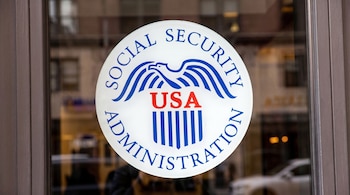 Un primer plano del logo circular blanco de la Administración del Seguro Social en una puerta de cristal, con un águila azul y rojo.