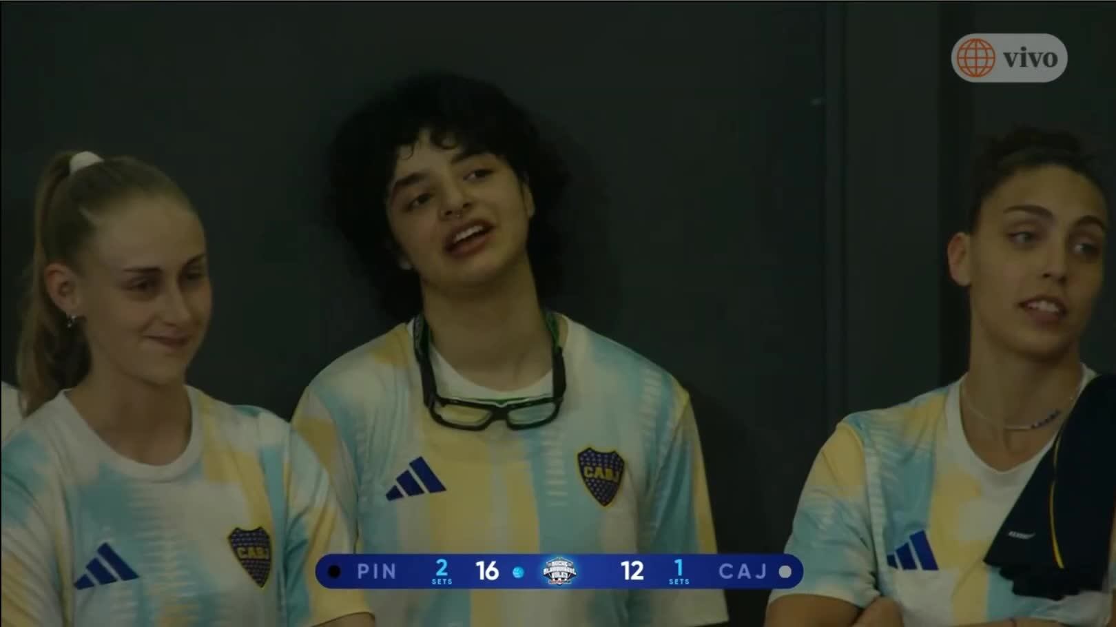 Las integrantes del equipo femenino de vóley de Boca Juniors esperan en la banca durante el encuentro amistoso de la Noche Blanquiazul. (América TV)