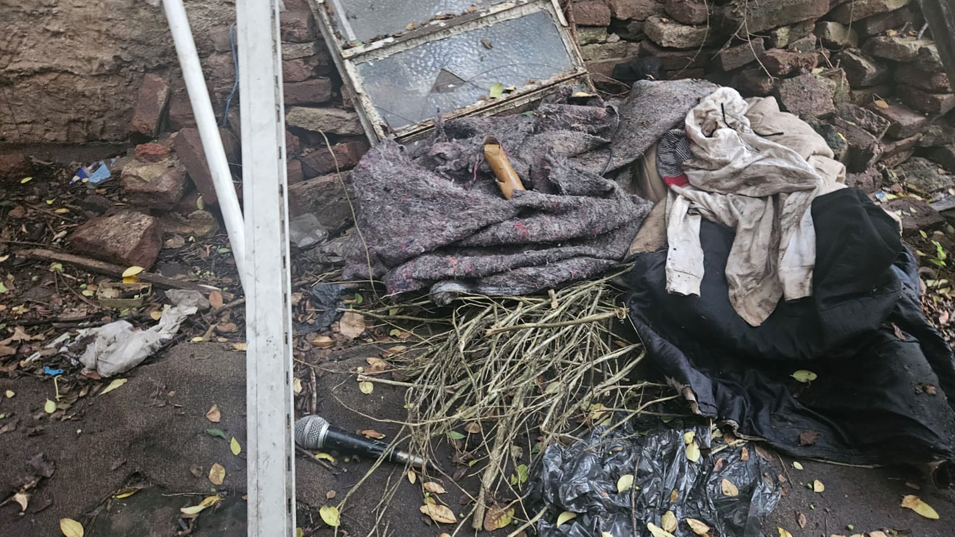 Un micrófono, ropa sucia y otros objetos personales yacen entre los escombros en la escena del crimen del rapero Mike Dee, parte de la investigación en curso.