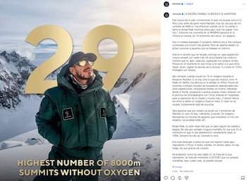 Hombre con chaqueta de invierno, gorra y gafas de sol posa frente a montañas nevadas y grandes números dorados '29'. Hay texto en inglés sobre cumbres de 8000m