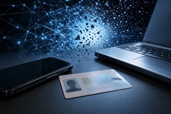 Una tarjeta de identidad sobre una mesa oscura junto a un teléfono inteligente, una computadora portátil y un gráfico de red digital.
