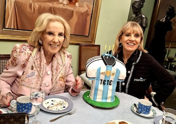 Mirtha Legrand y Teté Coustarot sonríen en una mesa con un pastel en forma de camiseta de fútbol de Argentina que dice "TETE", copas, tazas y platos