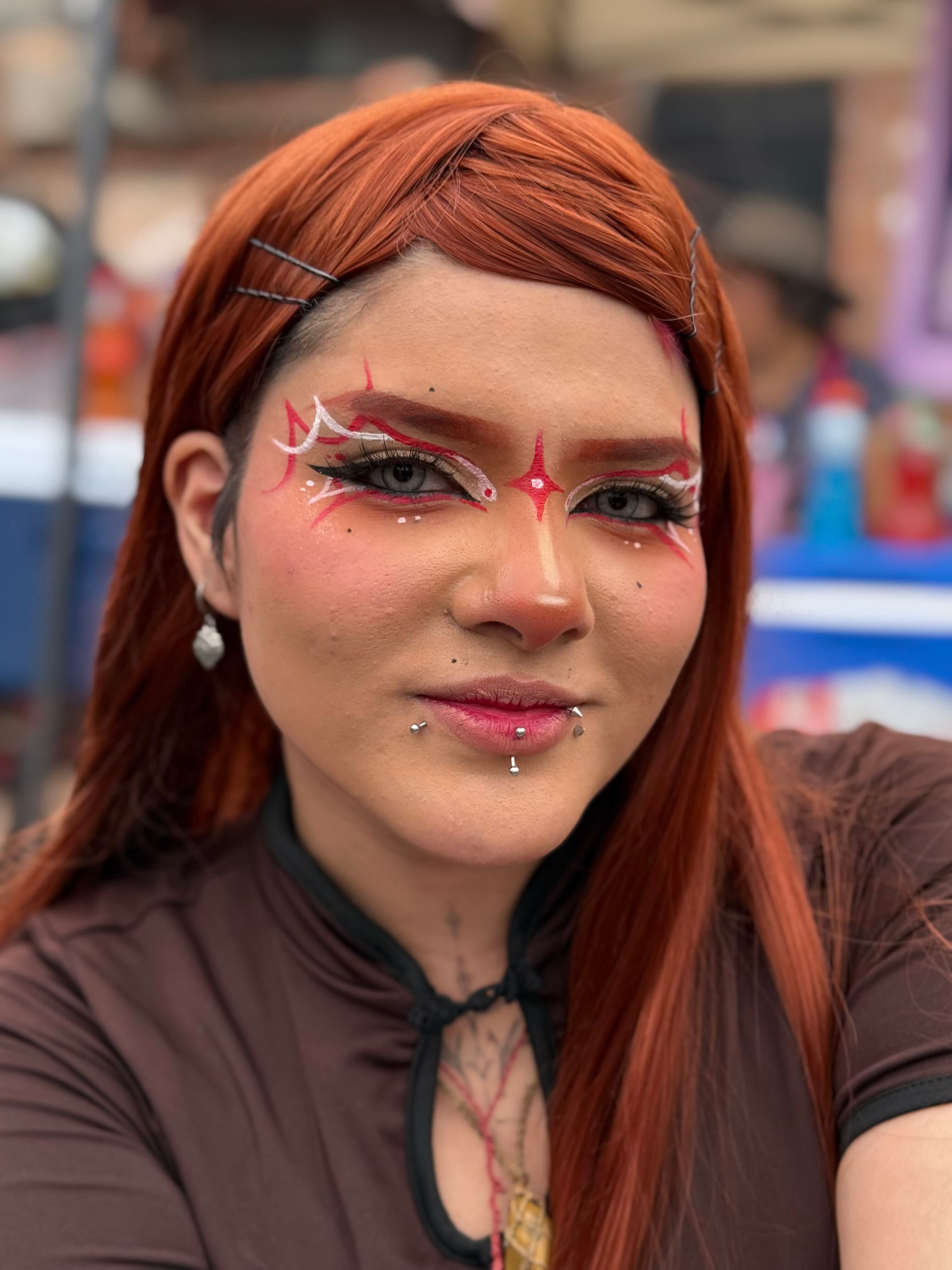 Una joven luce un maquillaje artístico y perforaciones faciales durante las actividades asociadas a un concierto en el Estadio San Marcos de Lima. (Paula Díaz)