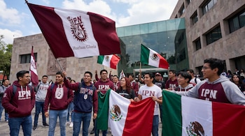 Grupo de jóvenes estudiantes con sudaderas del IPN sosteniendo banderas de México y del IPN frente a un edificio con fachada de piedra y cristal.