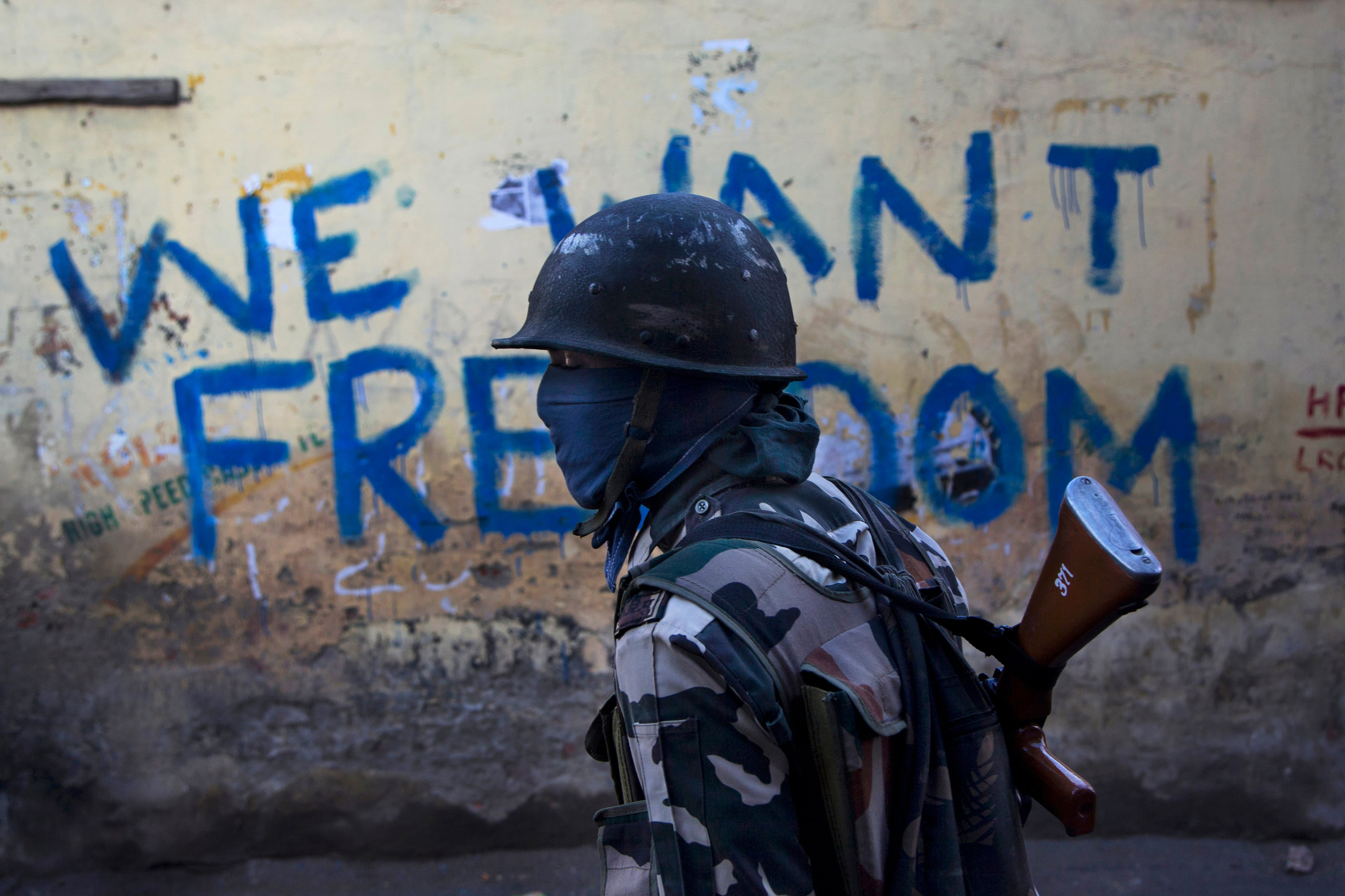 Un soldado paramilitar de la India frente a una pared con graffiti en Srinagar, Cachemira. (AP foto/Dar Yasin)