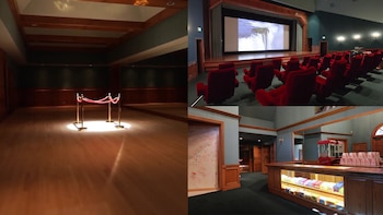 Un lujoso cine en casa con butacas de terciopelo rojo, una gran pantalla, un vestíbulo con suelo de madera, una barrera de cuerda y una barra de dulces