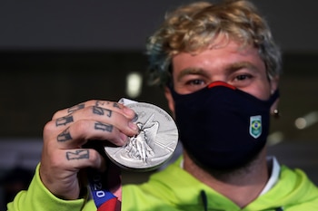Pedro Barros shows his silver medal which he won in the Men's Park Skateboarding at the Tokyo 2020 Olympics as he arrives at Sao Paulo International Airport in Guarulhos, in the outskirts of Sao Paulo, Brazil, August 7, 2021. REUTERS/Amanda Perobelli