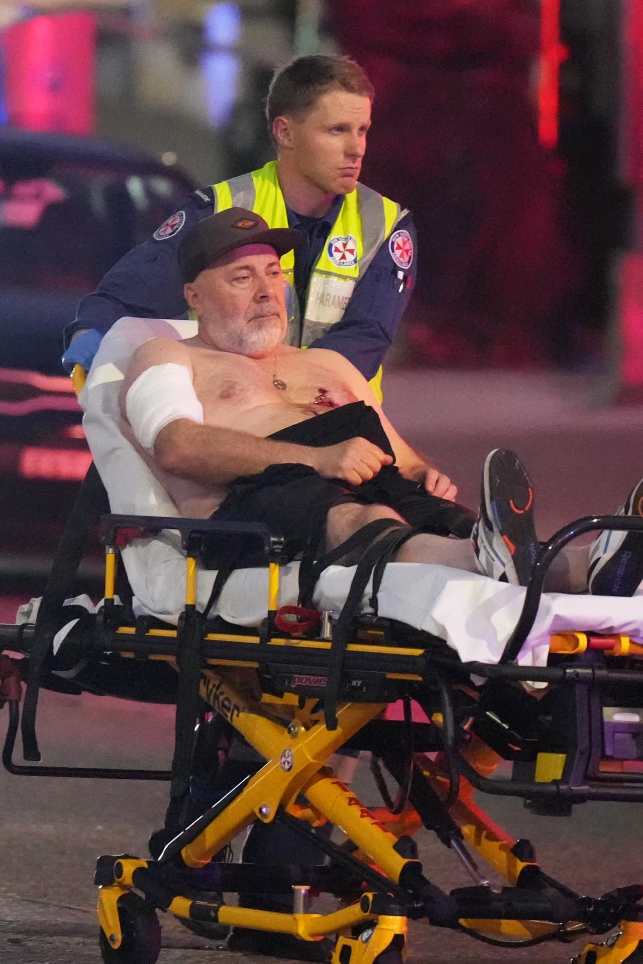 Un trabajador de emergencia empuja a una persona en una camilla después de un tiroteo reportado en Bondi Beach.