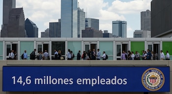 Cartel digital azul con '14,6 millones empleados' y logo Federal Reserve Bank de Dallas. Personas caminan frente a edificios de oficinas y rascacielos urbanos.