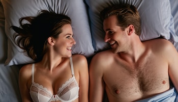 En una escena cargada de afecto, un hombre y una mujer jóvenes comparten risas y miradas llenas de amor mientras están acostados juntos en la cama, simbolizando la importancia de la intimidad, el enamoramiento y los fuertes vínculos emocionales en una relación. Esta imagen es un testimonio del poder de la conexión y el compromiso en el amor. (Imagen ilustrativa Infobae)