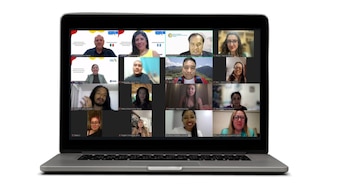 Una computadora portátil de color gris muestra una videollamada con múltiples participantes de diferentes edades y géneros en un fondo blanco