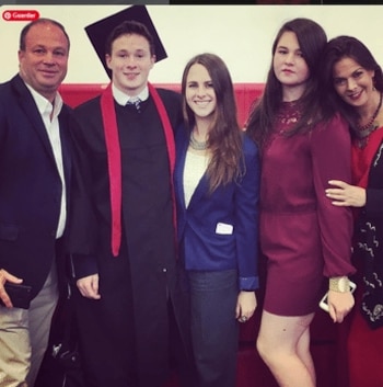 Cinco personas posan en una sala, entre ellas un joven que viste toga y birrete de graduación junto a un hombre y tres mujeres