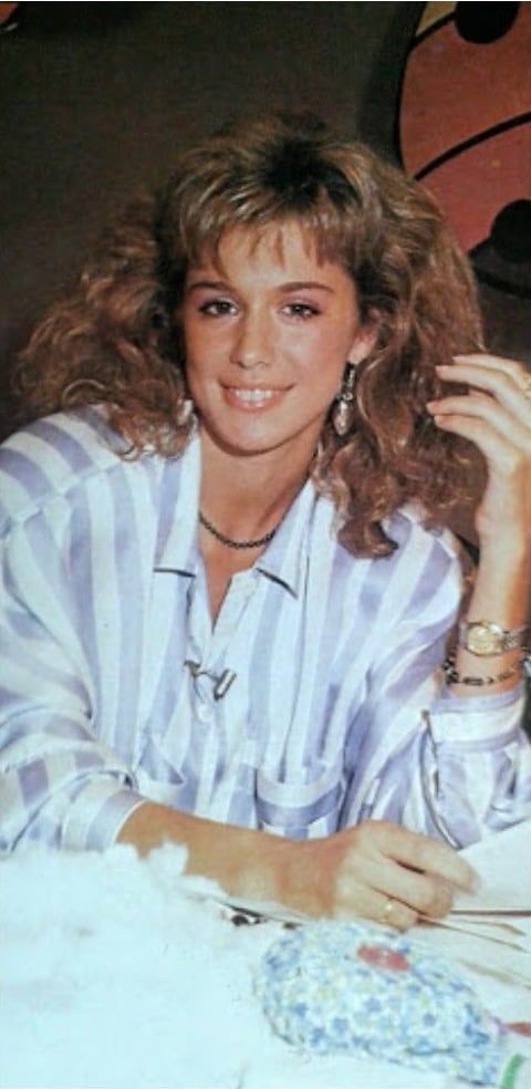 La reconocida presentadora y actriz Flavia Palmiero posa sonriente luciendo su distintivo cabello rizado y un atuendo casual de camisa a rayas.