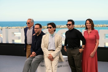 Cinco personas posan junto a letras blancas del festival SSIFF con el mar de fondo