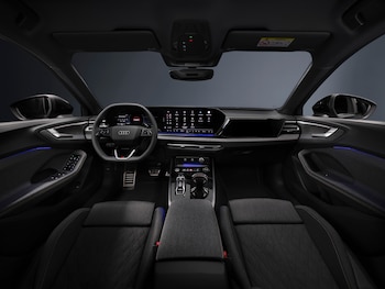 Interior de un automóvil con volante multifunción, panel digital, pantalla táctil central, consola, asientos y luz ambiental azul