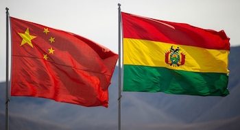 La bandera roja de China con cinco estrellas amarillas y la bandera de Bolivia, con franjas roja, amarilla y verde y su escudo central, ondean juntas.
