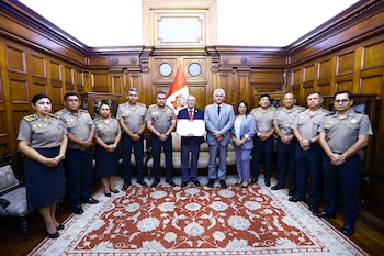 Fernando Rospigliosi y otros funcionarios, incluyendo miembros de la PNP en uniforme, posan en una sala de madera con alfombra roja y la bandera peruana
