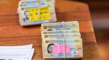 Múltiples pilas de Documentos Nacionales de Identidad de Perú atados con cuerdas y etiquetas de papel sobre una mesa de madera