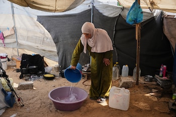 La palestina desplazada Reem Abu Lahia lava su ropa dentro de la tienda donde vive en Jan Yunis, en el sur de la Franja de Gaza, el jueves 30 de abril de 2026 (AP/Abdel Kareem Hana)