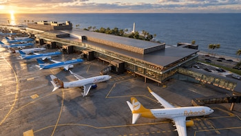 Aviones de Flybondi, JetSMART y Aerolíneas Argentinas aparcados en las pistas de un aeropuerto moderno frente a la costa al amanecer