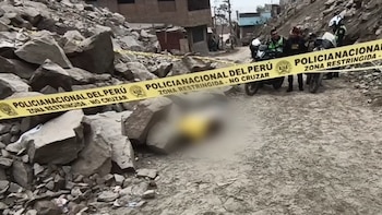 Camino de tierra con rocas, un cuerpo borroso en el suelo, cinta policial amarilla de "Policía Nacional del Perú" y agentes con motocicletas en la escena del crimen