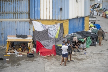 Varios migrantes se protegen de la lluvia con telas y lonas en la ciudad autónoma. (Europa Press)