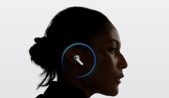 Primer plano de perfil de una mujer de piel oscura con un AirPod Pro blanco en su oído derecho, rodeado por un efecto de luz azul y verde