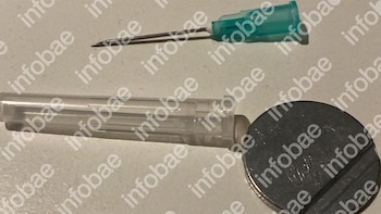 Dos agujas médicas, una con conector azul verdoso y la otra con capuchón transparente, junto a un objeto circular metálico, sobre fondo claro