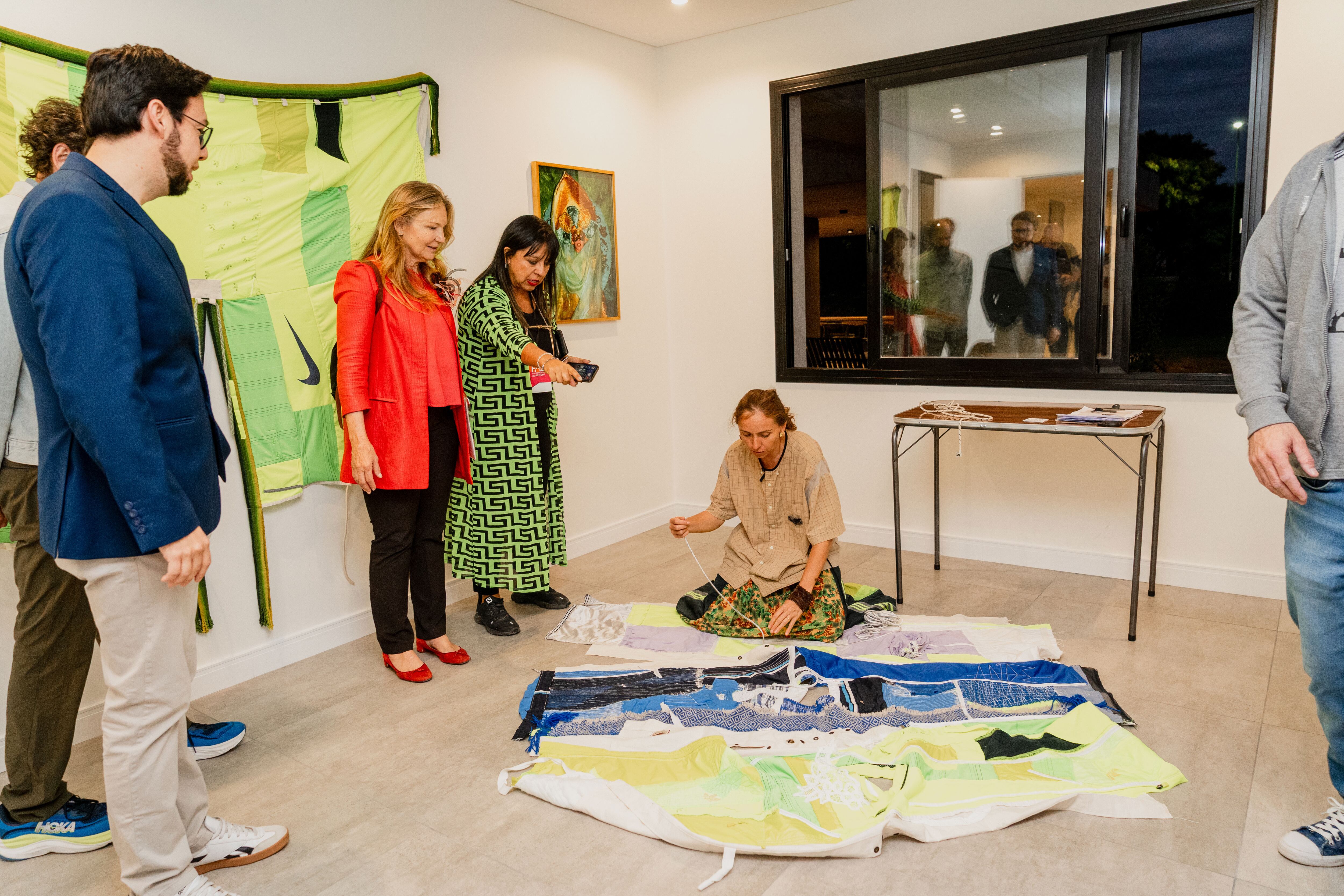 La artista Candelaria Aaset, de galería UNCU, en el piso, muestra las características del textil