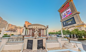 Vista del exterior del Caesars Palace con arquitectura clásica, estatuas, y una marquesina digital que muestra el nombre del hotel y un evento en Las Vegas