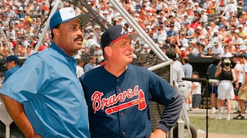 Cito Gaston, en chaqueta azul y gorra de Blue Jays, junto a Bobby Cox, en camiseta de los Braves, mirando a la derecha en un campo con gente