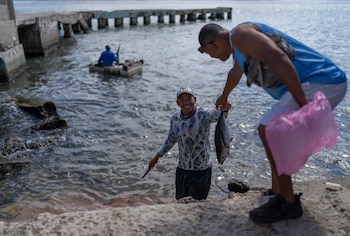 Un pescador entrega la pesca del día desde una balsa improvisada en el agua hasta la orilla en Cojimar, al este de La Habana, el miércoles 12 de marzo de 2025. (AP Foto/Ramón Espinosa)