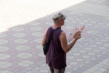Un turista se abanica en Sevilla. (EFE/ David Arjona)