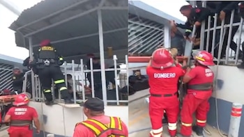 Policías y bomberos con uniformes rojos intervienen junto a una estructura metálica para auxiliar a un hombre