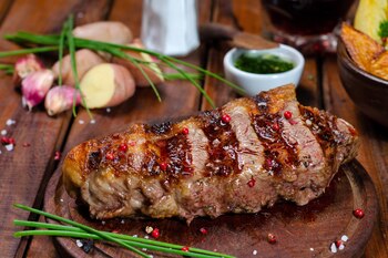 Bife de chorizo de carne argentina sobre un plato de madera, apoyado en una mesa