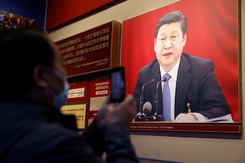 Un hombre sostiene un teléfono móvil frente a una imagen del presidente chino Xi Jinping expuesta en el Museo del Partido Comunista de China en Pekín, China 11 de noviembre de 2021. REUTERS/Carlos García Rawlins
