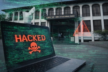 Un ordenador portátil muestra la palabra "HACKED" en rojo y un símbolo de calavera. Al fondo, la fachada de la Corte de Constitucionalidad.