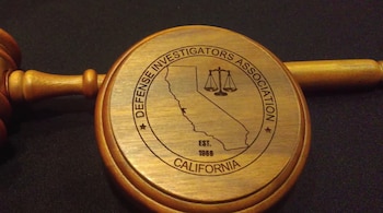 Mazo de juez y base circular de madera grabada con el mapa de California, una balanza de la justicia y texto en inglés sobre fondo oscuro
