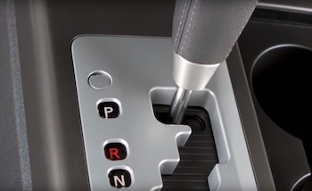 Algunos modelos esconden el botón de liberación tras una pequeña tapa junto a la palanca de cambios, accesible solo con una herramienta plana - crédito Transporte.MX