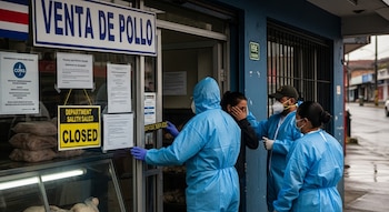 Fachada de un local de venta de pollo con un cartel de 'CLOSED'. Tres personas con trajes de bioseguridad y mascarillas están en la entrada.