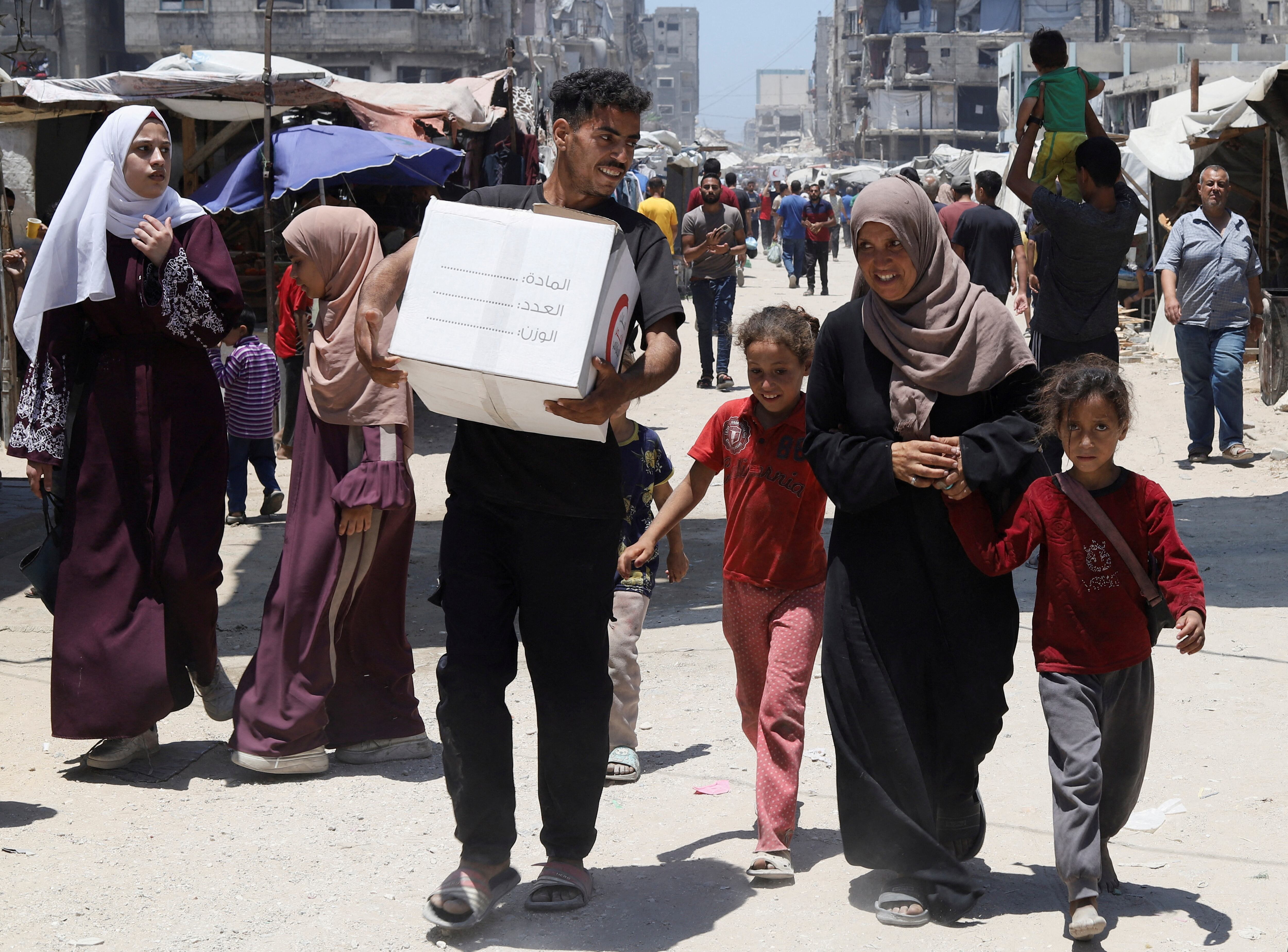 Una familia palestina con ayuda distribuida por la Media Luna Roja de los Emiratos, en la ciudad de Gaza, el 26 de junio de 2025. (REUTERS/Khamis Al-Rifi/archivo)