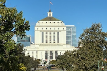 Edificio blanco con la inscripción Alameda County Court House, coronado por una bandera de Estados Unidos y rodeado de árboles