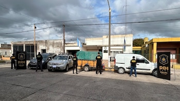 Agentes con camisetas DDI frente a varios vehículos (dos SUVs, un remolque, una furgoneta) y carteles DDI Azul en una calle con edificios
