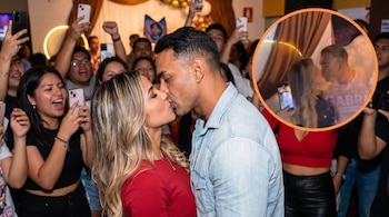 Una pareja se besa de perfil mientras es fotografiada por varias personas con teléfonos móviles; un círculo con borde naranja contiene otra foto de una pareja besándose.